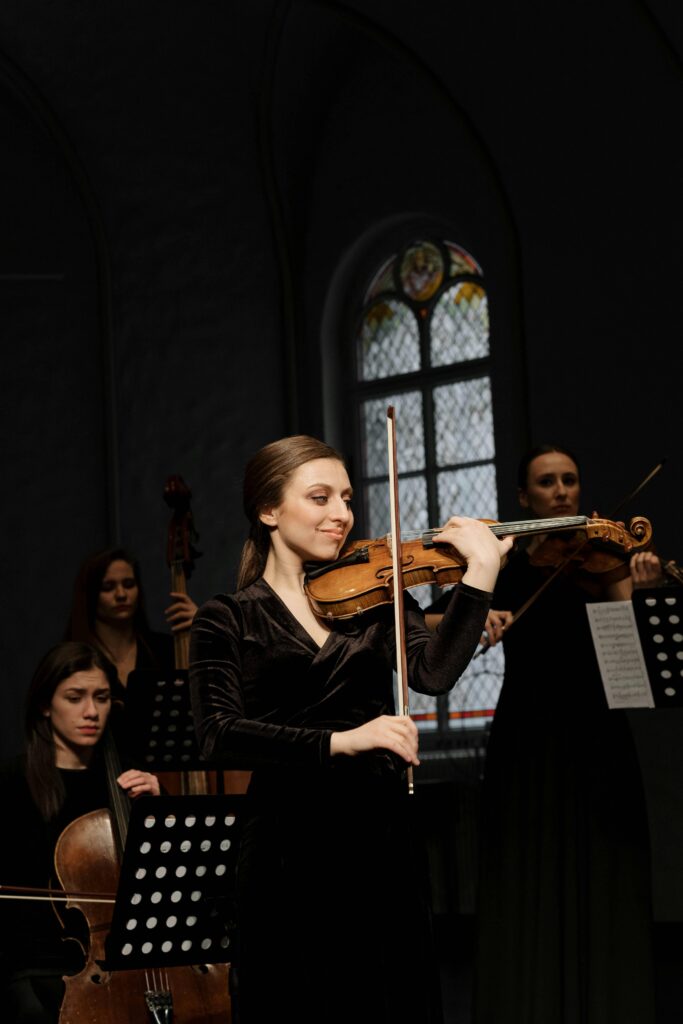Group of female musicians playing classical music with violins and cello indoors.